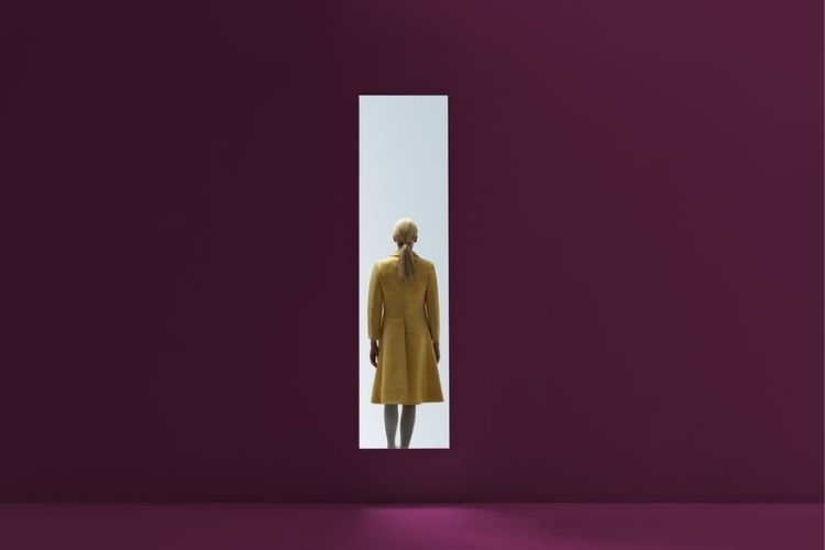 woman walking into rectangular opening in coloured wall