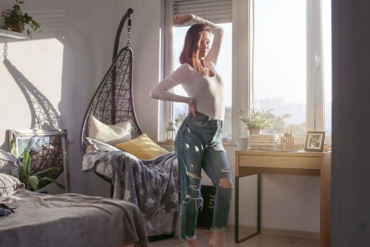 Attractive woman in blue jeans looking herself in front of mirror